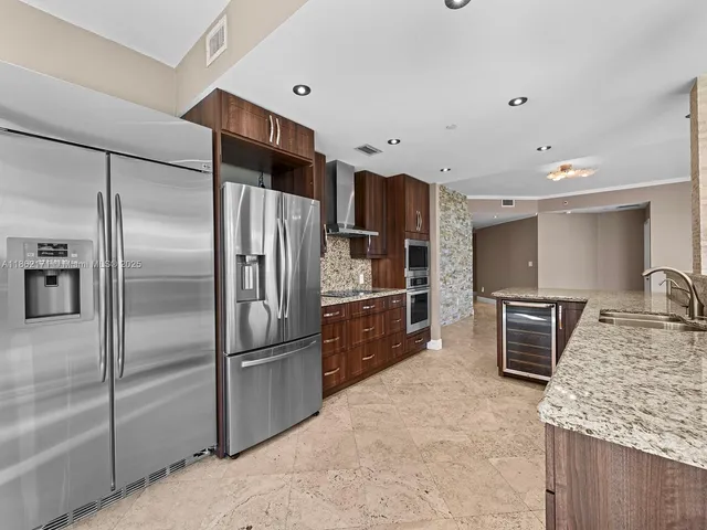 a kitchen with stainless steel appliances granite countertop a refrigerator and a sink