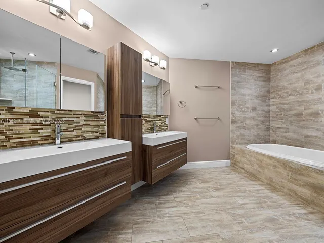 a bathroom with a double vanity sink a toilet and bathtub