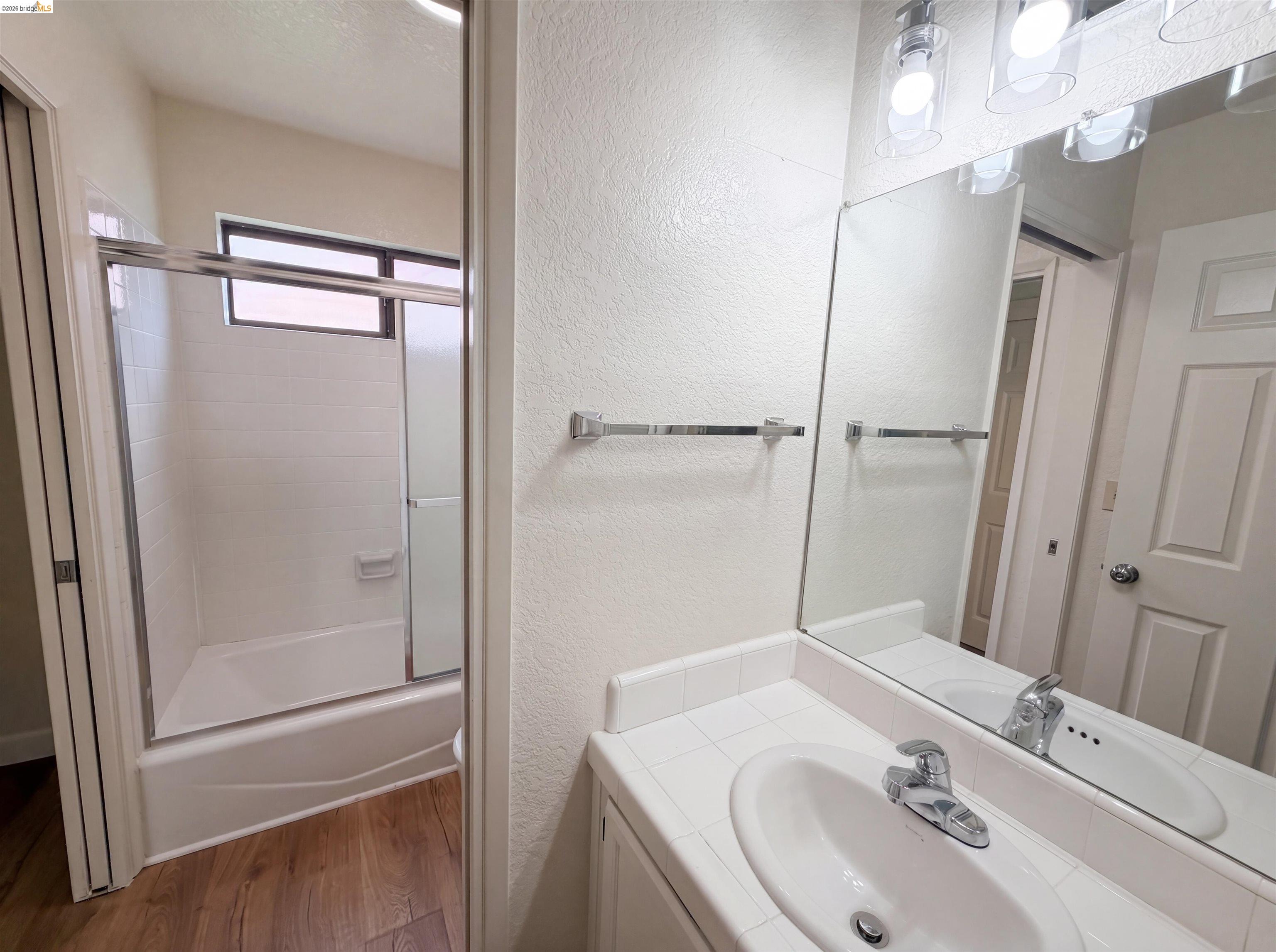1555 Hecker Pass Road, Unit C101 Gilroy, CA 95020 - Photo 11 of 18 Bathroom featuring a white vanity with an integrated sink and chrome faucet, a large mirror, and a three-light vanity fixture
