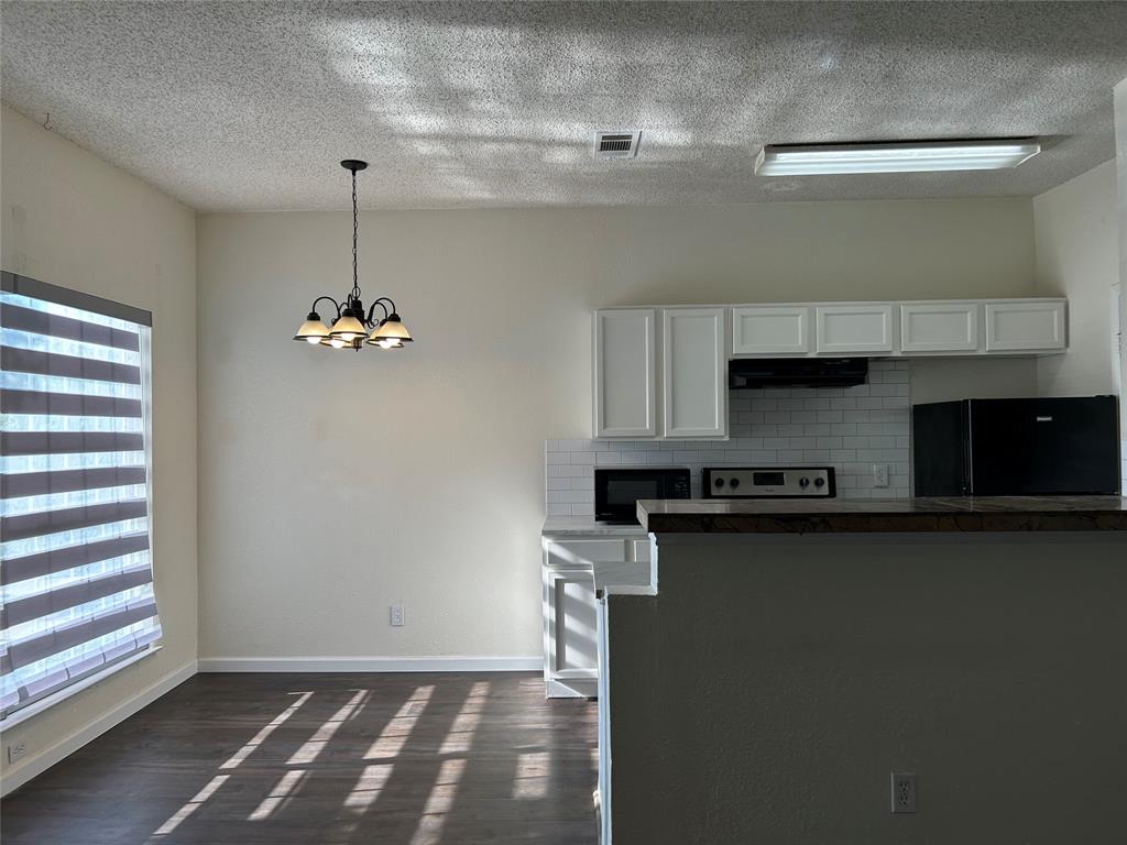 4107 Esters Road Irving, TX 75038 - Photo 14 of 21 Open-concept kitchen and dining area featuring wood-finish flooring, white shaker-style cabinetry, and a subway tile backsplash