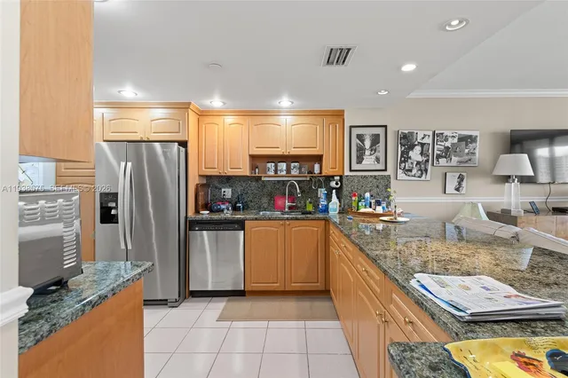 a kitchen with stainless steel appliances granite countertop a refrigerator a stove and a sink
