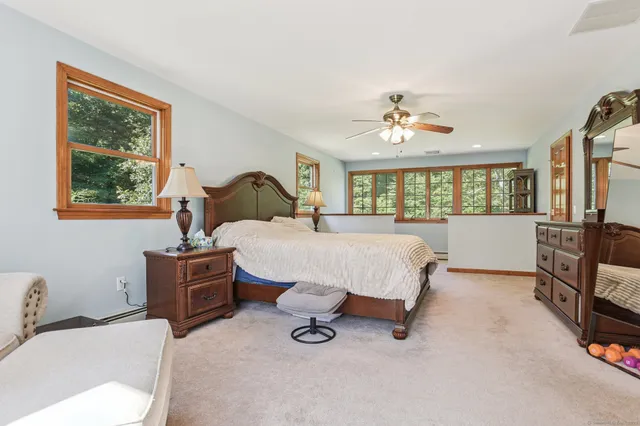 a spacious bedroom with a bed a dresser and a chandelier