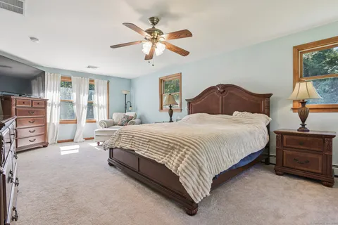 a spacious bedroom with a bed a dresser and a chandelier