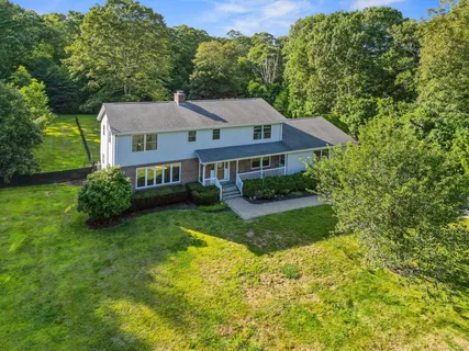 a view of a house with a big yard plants and large trees