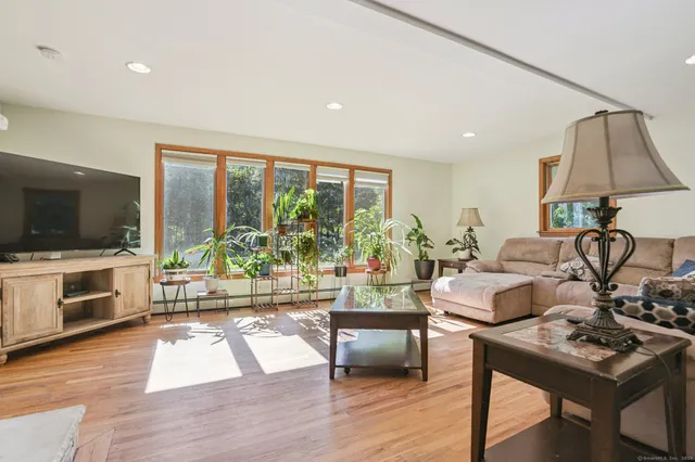 a living room with furniture a flat screen tv and a floor to ceiling window