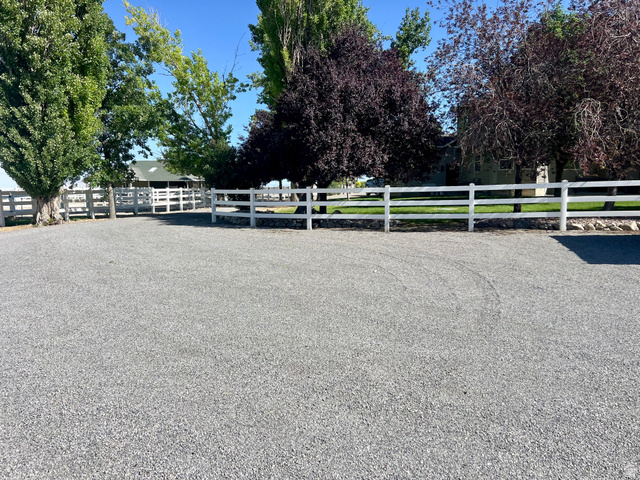 812 East Bates Cyn Road Tooele, UT 84074 - Photo 4 of 144 Gravel drive with white three-rail fencing, bordered by mature trees and verdant lawns