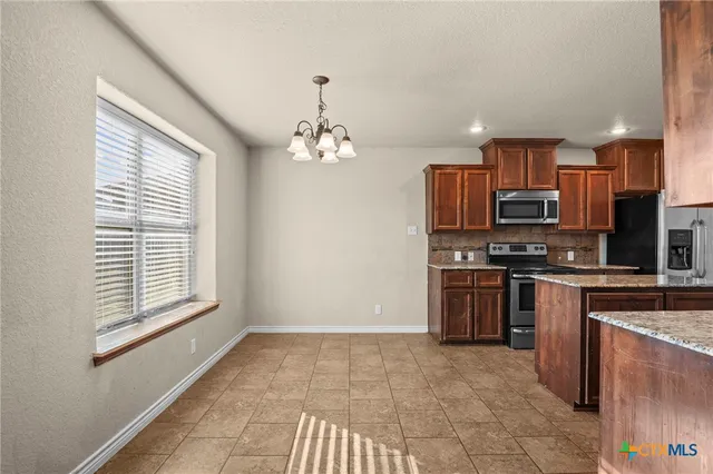 a kitchen with stainless steel appliances granite countertop a stove top oven a sink a counter space and cabinets