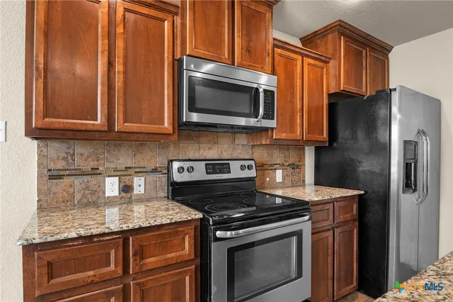 a kitchen with stainless steel appliances granite countertop a stove microwave and refrigerator