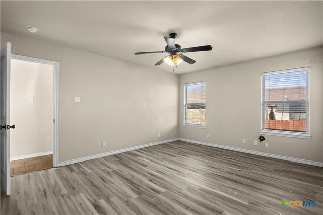 a view of empty room with wooden floor and fan