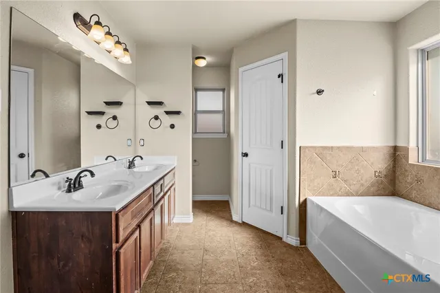 a bathroom with a tub sink double vanity and mirror