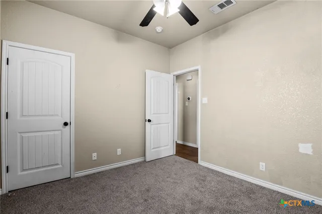 an empty room with a ceiling fan and entryway
