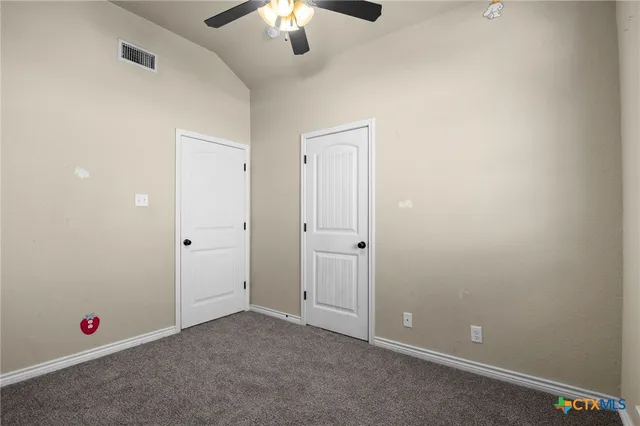 an empty room with chandelier fan and closet