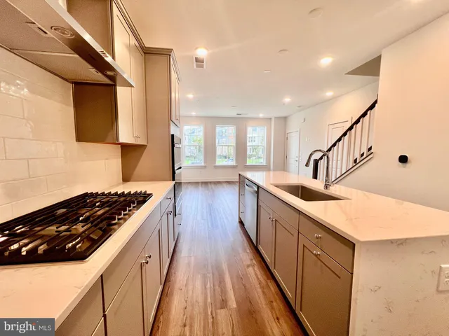 a kitchen with sink a stove and wooden floor
