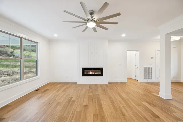 a view of an empty room with wooden floor and a fireplace