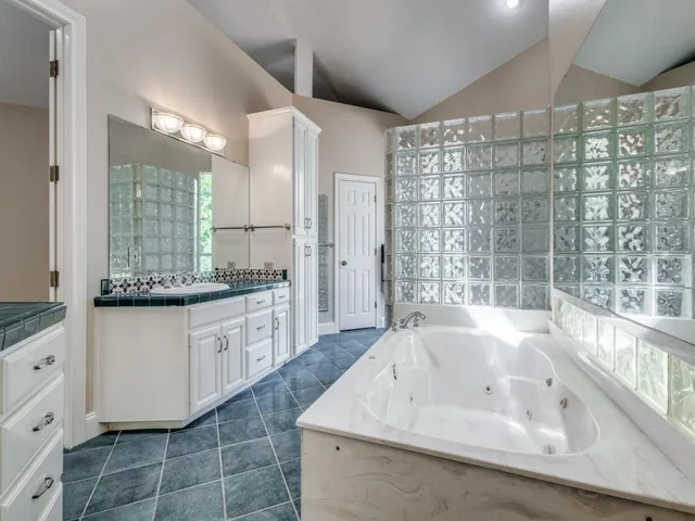 a spacious bathroom with a granite countertop double vanity sink a mirror and a bathtub