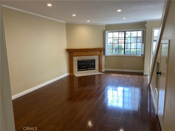 an empty room with wooden floor fireplace and windows