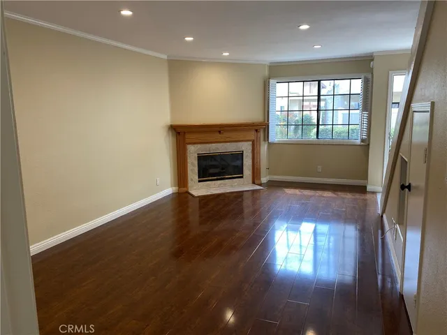 an empty room with wooden floor fireplace and windows