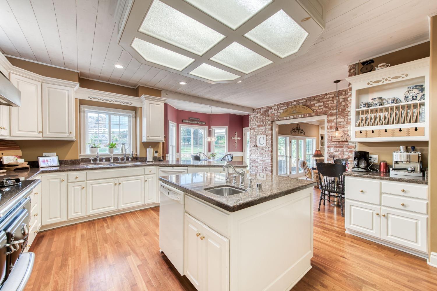 21672 Westmere Lane Friant, CA 93626 - Photo 23 of 80 a kitchen with stainless steel appliances granite countertop hardwood floor sink stove dining table and chairs