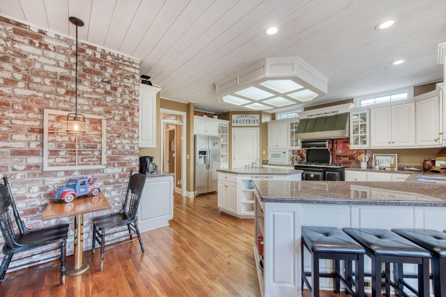21672 Westmere Lane Friant, CA 93626 - Photo 25 of 80 a kitchen with stainless steel appliances granite countertop a stove top oven a sink a dining table and chairs with wooden floor