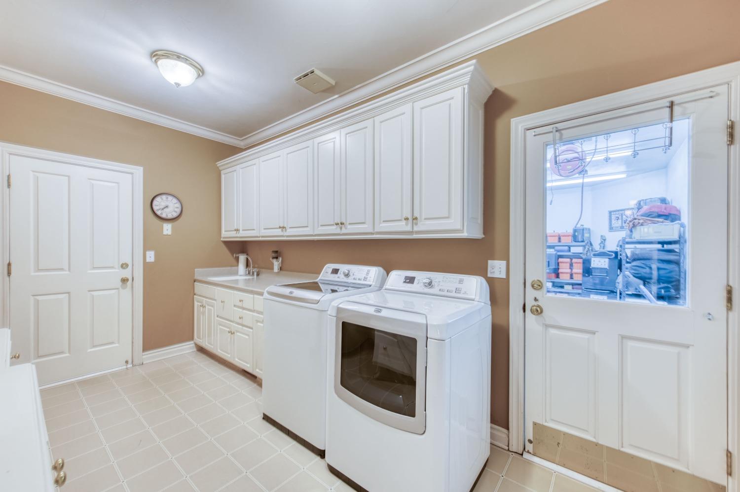 21672 Westmere Lane Friant, CA 93626 - Photo 32 of 80 a utility room with cabinets washer and dryer