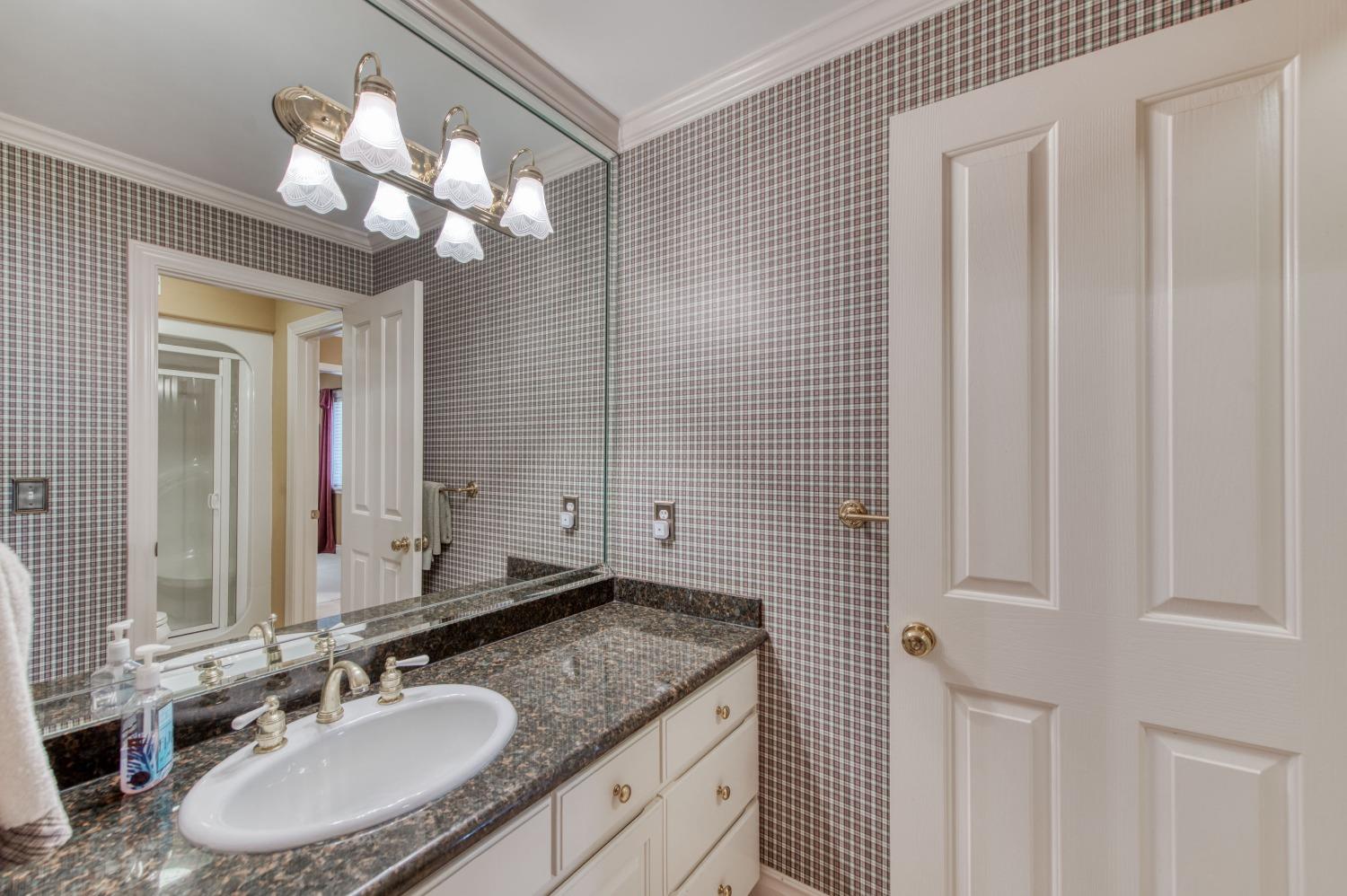 21672 Westmere Lane Friant, CA 93626 - Photo 37 of 80 a bathroom with a granite countertop sink a light fixture and a mirror