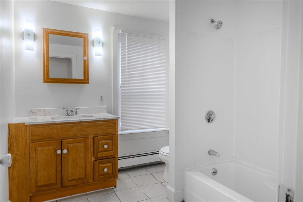 34 Perkins Street, Unit 2 Gloucester, MA 01930 - Photo 4 of 19 a bathroom with a granite countertop sink a mirror and a bathtub