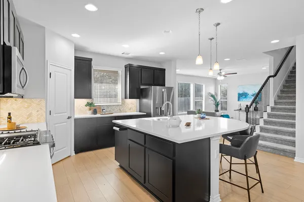 a kitchen with a sink a center island stainless steel appliances and cabinets