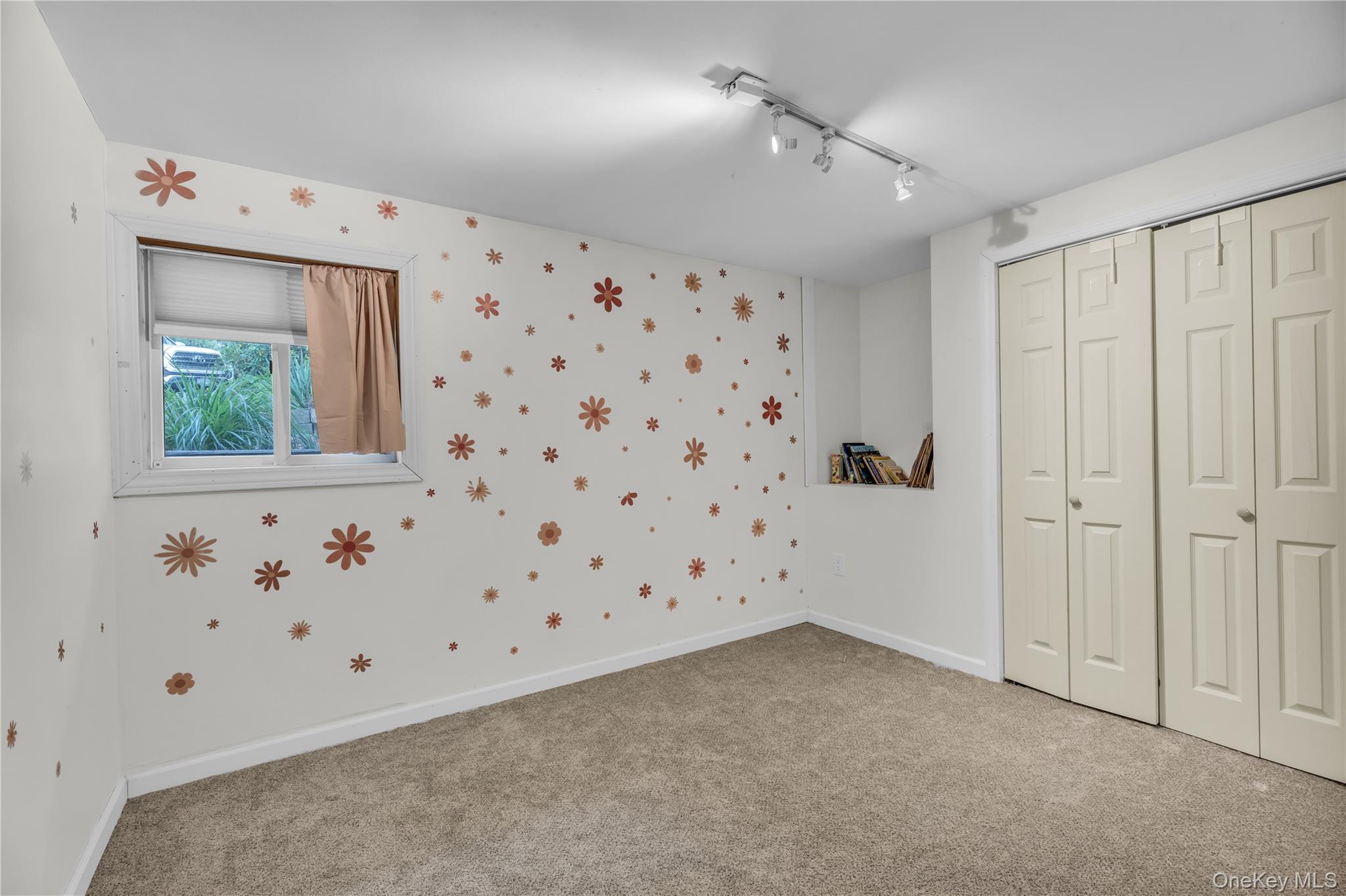 64 Sally Lane Ridge, NY 11961 - Photo 14 of 18 Unfurnished bedroom with a closet, light colored carpet, rail lighting, and wallpapered walls