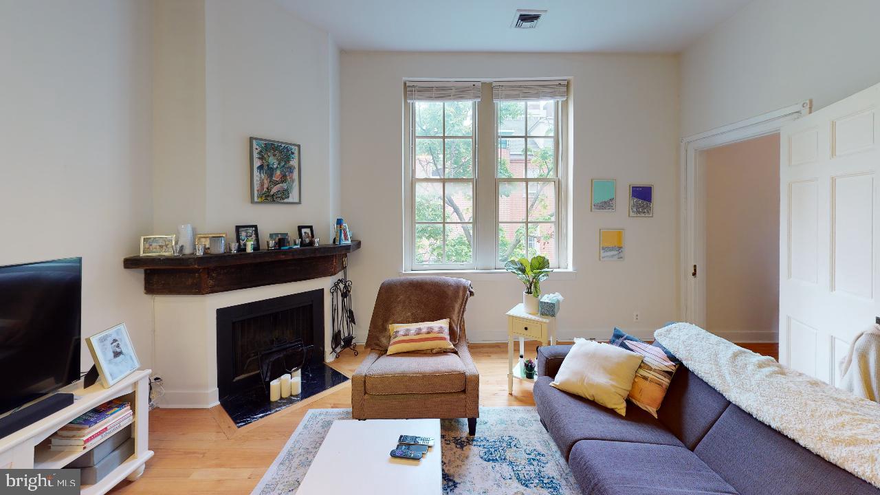 260 South 9th Street, Unit 2F Philadelphia, PA 19107 - Photo 1 of 8 a living room with furniture a flat screen tv and a fireplace