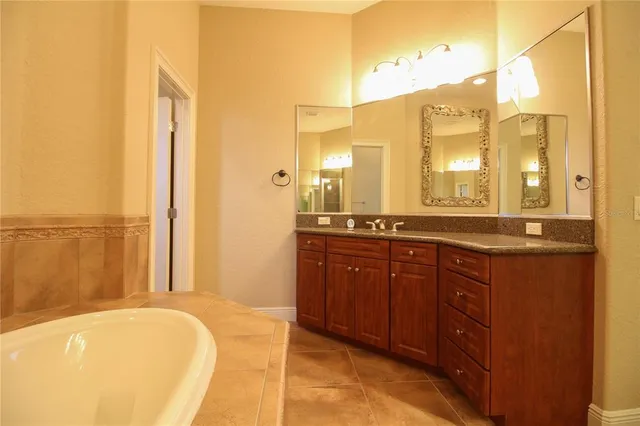a spacious bathroom with a tub sink and mirror