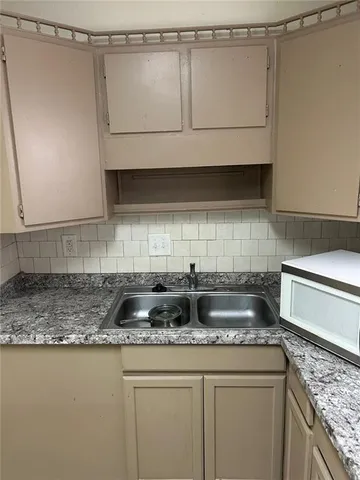 a kitchen with granite countertop a sink a stove and cabinets