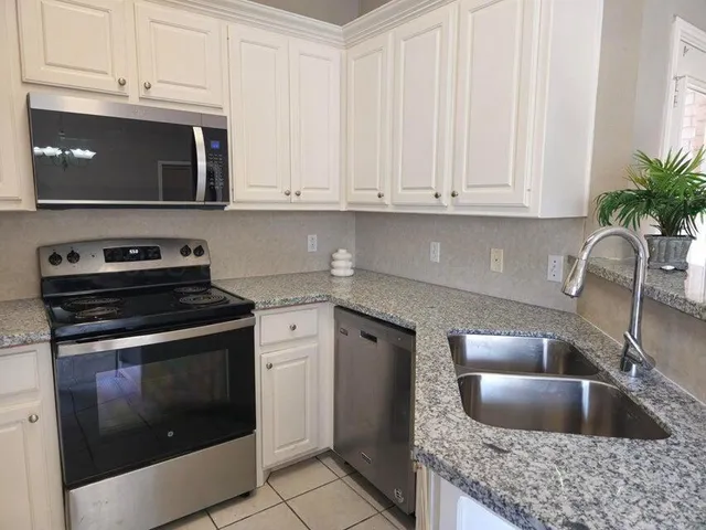 a kitchen with granite countertop a stove sink and microwave