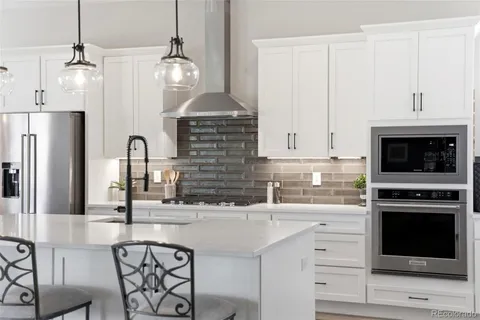 a kitchen with stainless steel appliances a stove a sink and a refrigerator with white cabinets