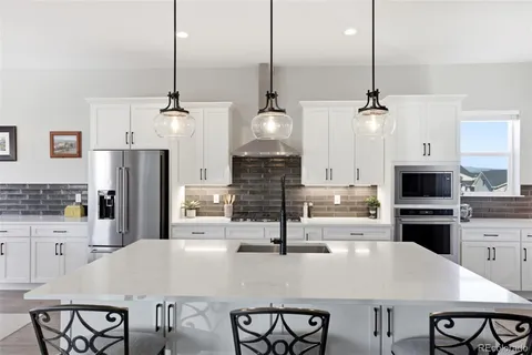 a kitchen with stainless steel appliances kitchen island granite countertop a dining table chairs and refrigerator