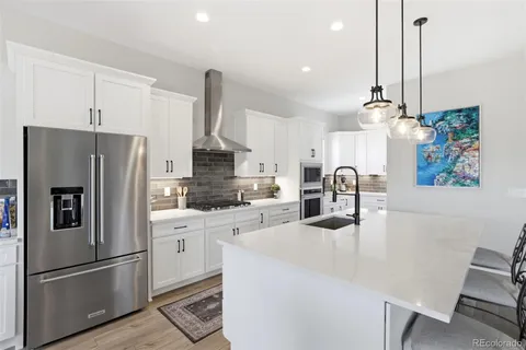 a kitchen with refrigerator a stove a sink and white cabinets