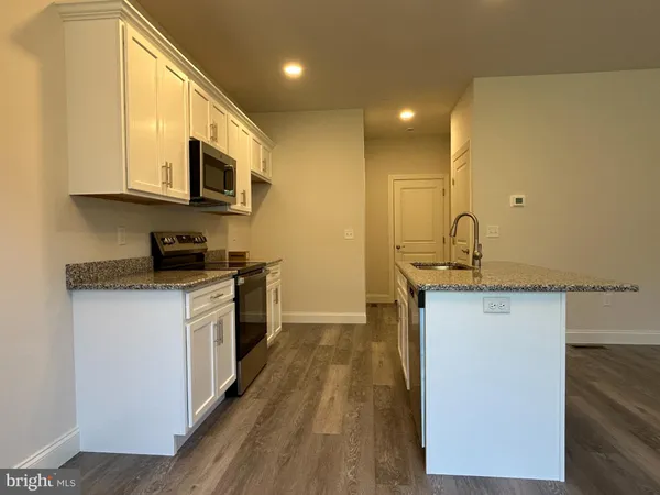 a kitchen with stainless steel appliances granite countertop a sink a stove top oven a counter space and cabinets