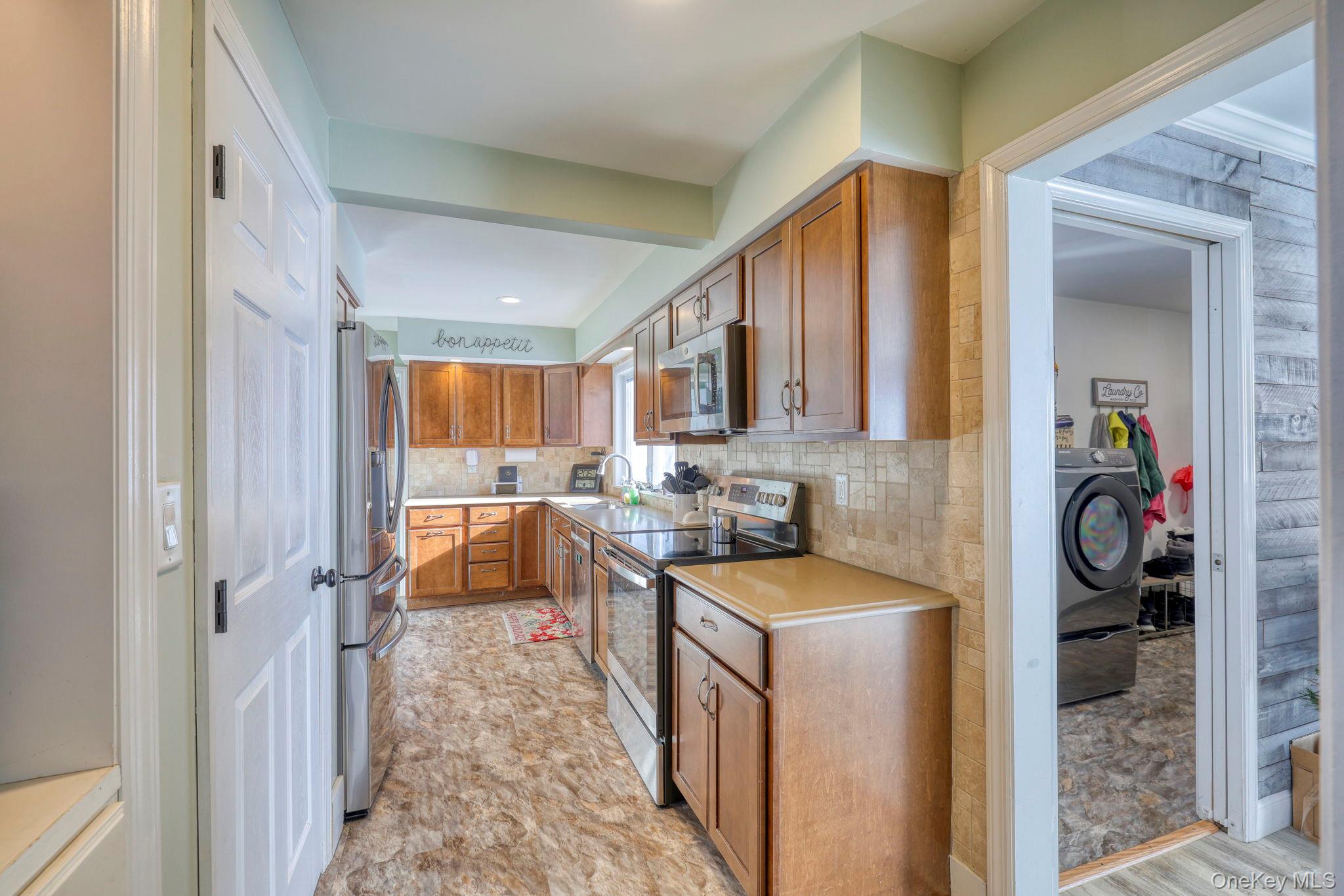 210 Overlook Road Poughkeepsie, NY 12603 - Photo 18 of 43 Kitchen with brown cabinets, stainless steel appliances, light countertops, washer / clothes dryer, and backsplash