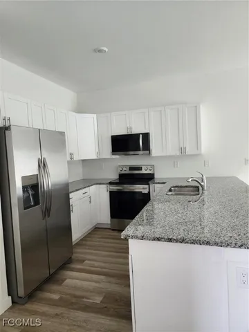 a kitchen with granite countertop a refrigerator a sink a stove a microwave and island