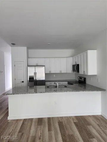 a large white kitchen with kitchen island granite countertop a sink and white cabinets