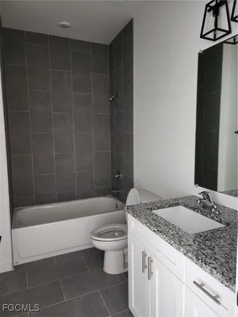 a bathroom with a granite countertop sink a toilet and bathtub