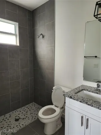a bathroom with a granite countertop toilet a sink and a mirror