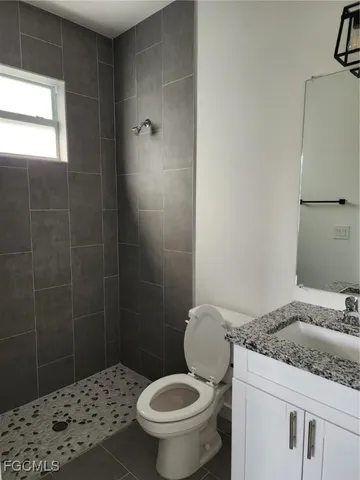 a bathroom with a granite countertop toilet a sink and a mirror