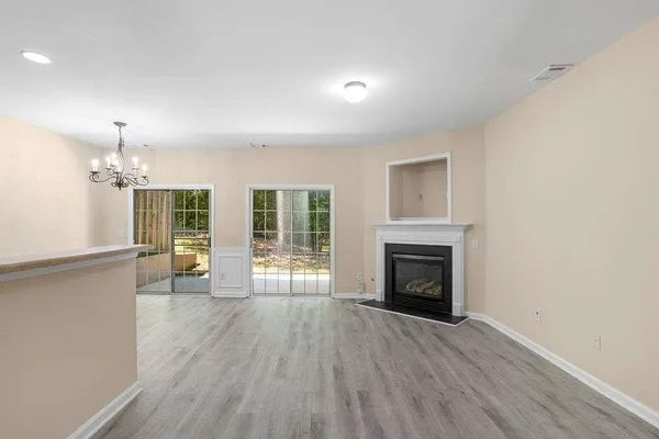 an empty room with wooden floor fireplace and windows