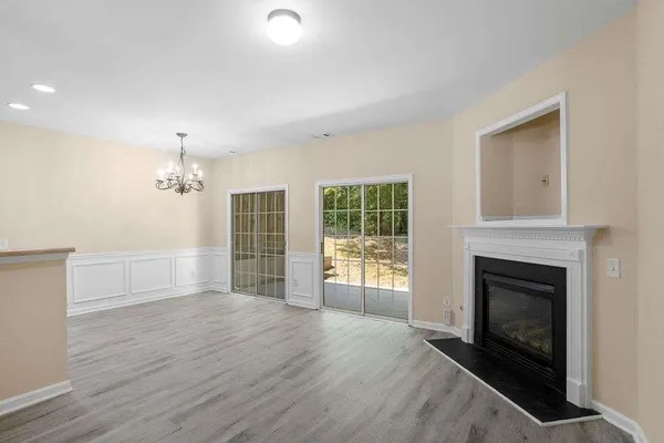 a view of an empty room with wooden floor fireplace and a window