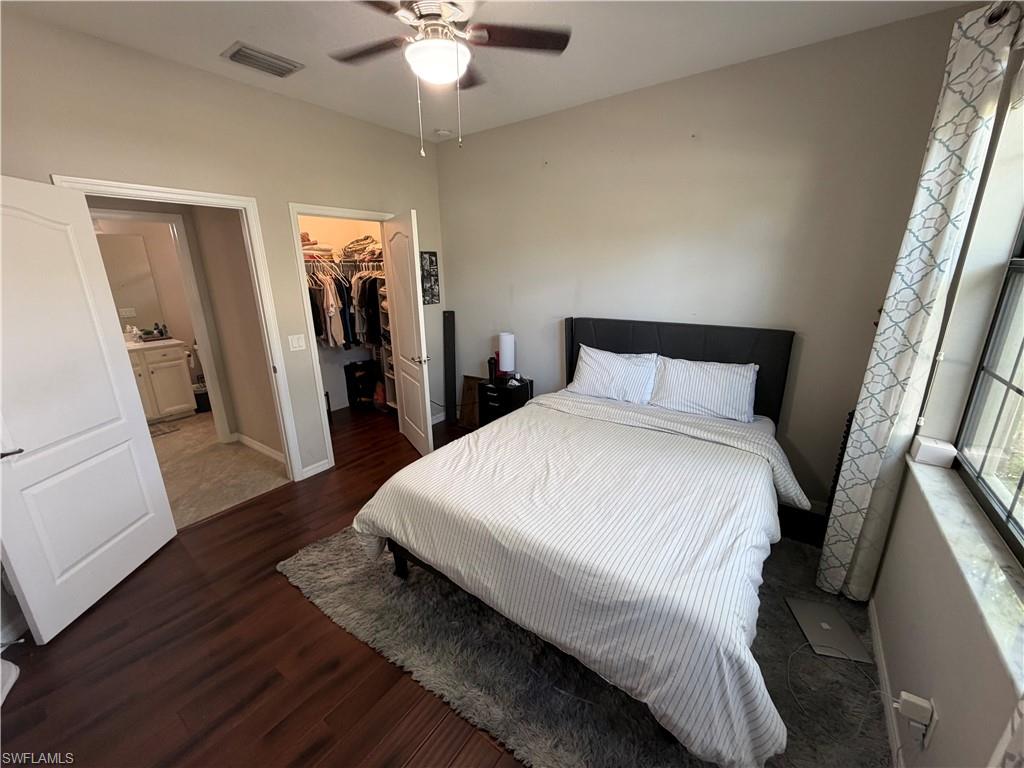 4284 Raffia Palm Circle Naples, FL 34119 - Photo 12 of 50 Bedroom with dark wood finished floors, a spacious closet, and a ceiling fan