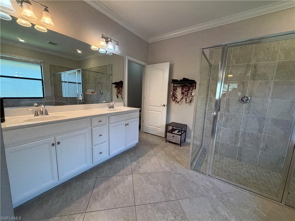 4284 Raffia Palm Circle Naples, FL 34119 - Photo 34 of 50 Master bath with double vanity, crown molding, and a shower stall