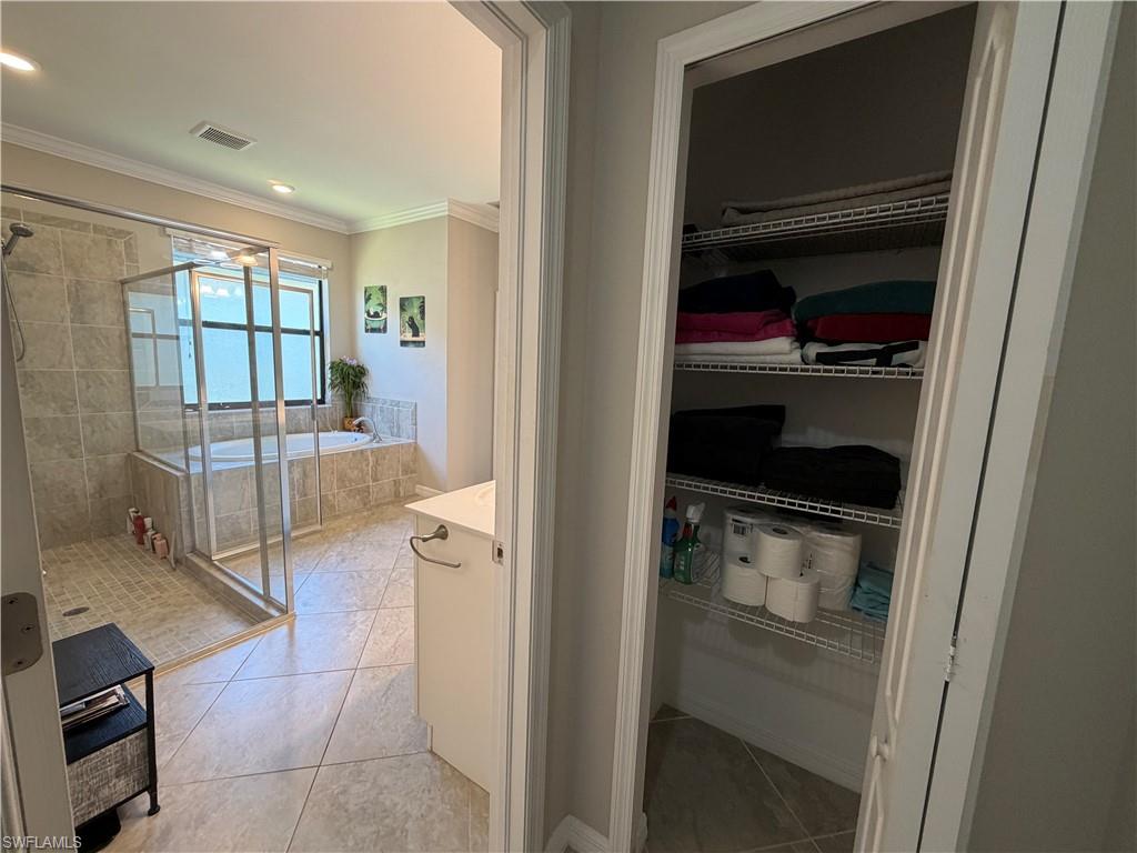 4284 Raffia Palm Circle Naples, FL 34119 - Photo 40 of 50 Bathroom featuring vanity, a stall shower, light tile patterned floors, a bath, and crown molding