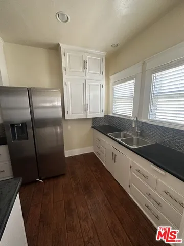 a kitchen with granite countertop a refrigerator sink and cabinets