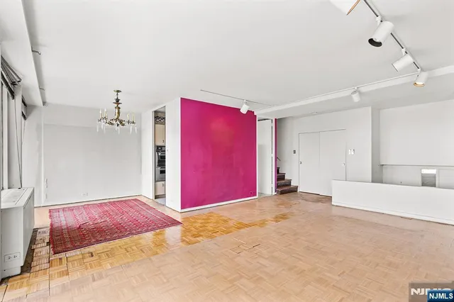 a view of an empty room with a chandelier fan