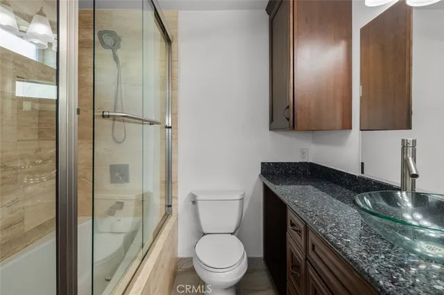 a bathroom with a granite countertop toilet a sink and a mirror